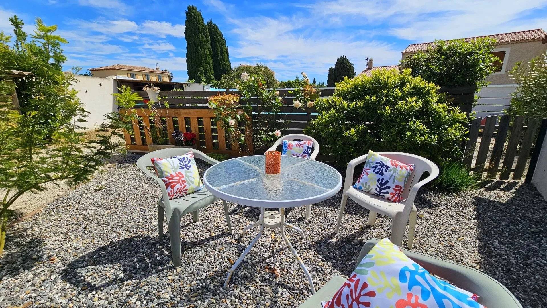 Aménagement d'un espace détente avec table et coussins colorés. Un home staging signé Attraction Immobilière à Hyères pour sublimer les extérieurs de cette villa et provoquer le coup de cœur immédiat de l'acquéreur.